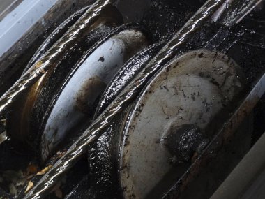 Yağlı endüstriyel metal dişlilerin dönüşünü gösteren yakın plan.