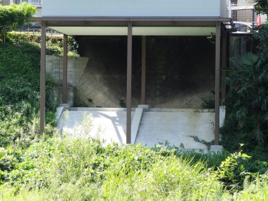 Beton yamaç ve yeşilliğin üzerindeki yüksek ev yapısı