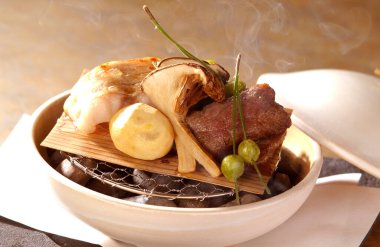 Biftek mantarı sebze ve garnitür içeren dumanı tüten gurme bir yemek.