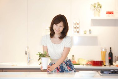 Asyalı kadın mutfakta yemek pişiriyor.