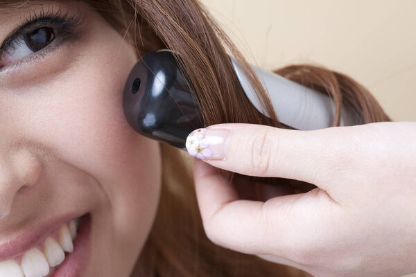 cropped shot of woman making hair swirls on light background