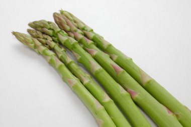 Arka planda taze yeşil kuşkonmaz izole edilmiş, yakın plan.