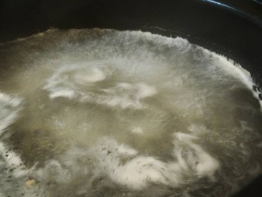 Bir tavada kaynayan suyun yakın plan çekimi. 