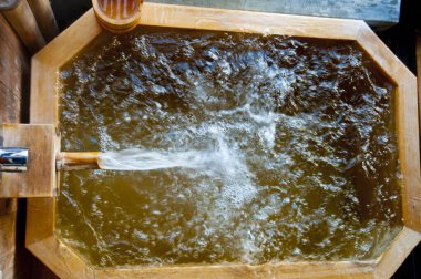 Kabaran su ve buharla dolu ahşap jakuzi.