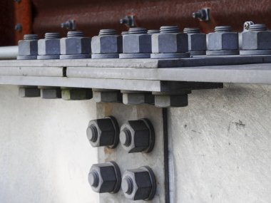 Çelik inşaat kirişlerini koruyan büyük metal cıvataları gösteriyor.