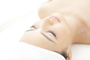 Beyaz havluyla uzanan kadın gözleri kapalı.