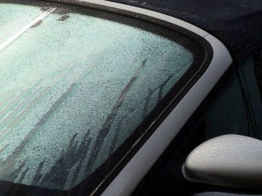 Sabah güneş ışığı çiğ kaplı araba penceresine vuruyor.