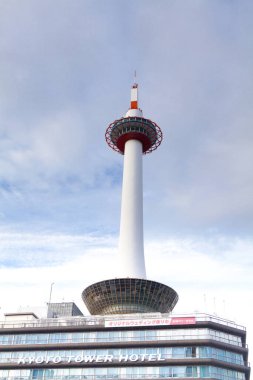 Bulutlu gökyüzünün altında modern şehir binasının üzerinde yükselen uzun gözlem kulesi
