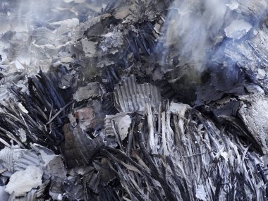 Yanan molozlar yanmış odun külleri ve yükselen dumanlar gösteriyor.