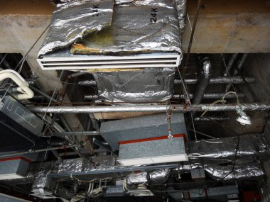 Hasarlı izolasyon borularını gösteren endüstriyel tavan.