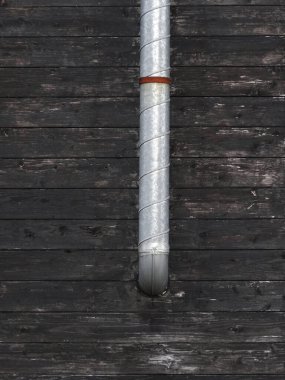 Dikey metal boru eskimiş, ahşap duvar boyunca uzanıyor.