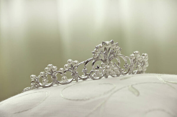Sparkling silver tiara resting atop elegant white cushion surface