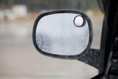 Şehirde yağmur damlaları olan araba aynasının yakın görüntüsü