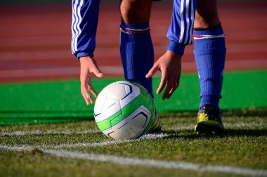 Bir futbolcu sahada futbol topunu tekmeliyor.