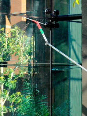 Açık havada uzun saplı cam camları temizliyorum.