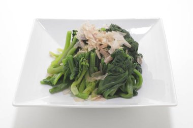 Beyaz bir tabakta yeşil sebzelerin yakın plan fotoğrafı.