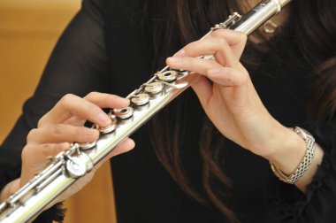 Gümüş tuşlarla flüt çalan kadın.