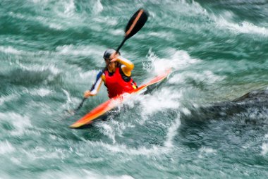 Aydınlık bir yaz gününde dalgalı sularda gezen kanocu.