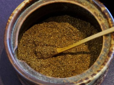 Köy baharatları kırsal seramik kavanozu tahta kaşıkla dolduruyor.