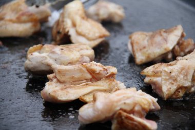 Sizzling chicken pieces cooking on hot metal surface