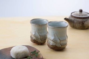 Çaydanlık ve pastanın yanında seramik çay fincanları