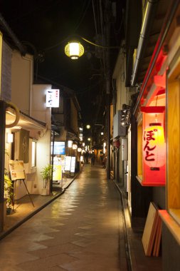 Gece parlayan fenerlerle aydınlatılmış dar Japon sokağı.