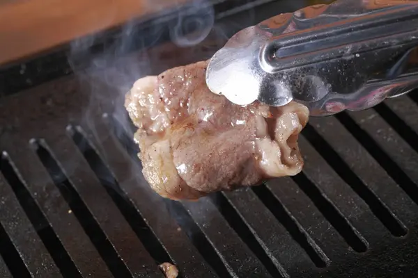 用厨房钳在烤架上烹调猪肉 — 图库照片
