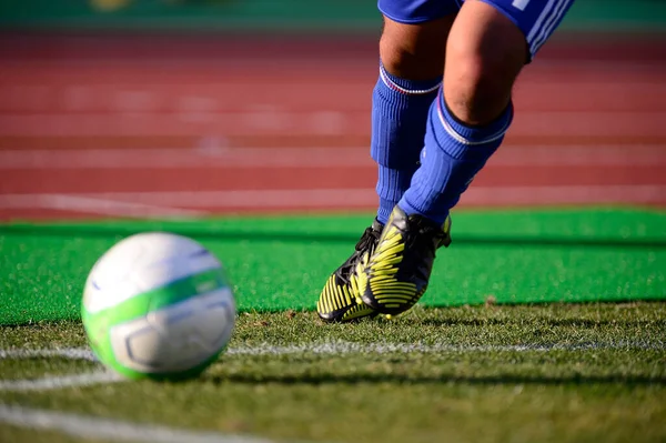 Bir futbolcu sahada futbol topunu tekmeliyor.