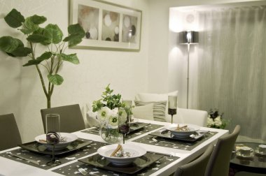 Akşam saatlerinde modern bir iç mekanda çiçek süsü ve ortam aydınlatmasıyla şık bir yemek düzeni.