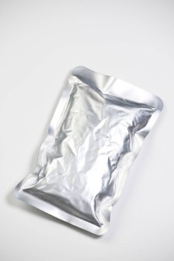 Sealed metallic pouch resting against plain white background