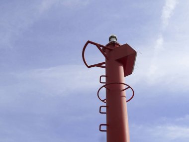 Mavi arka planda duran uzun kırmızı deniz feneri