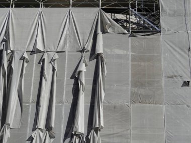 Katlanmış şemsiyeler büyük gri inşaat brandasına asılı.