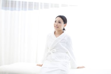 Kanepede oturan beyaz cüppeli güzel Asyalı kadın.