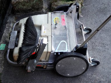 Endüstriyel zemin süpürücü sert kaldırım yüzeyinde dinleniyor.