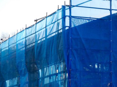 İnşaat alanı mavi iskele ve ağlarla kaplı.