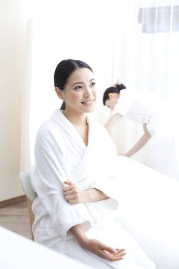 Kaplıcada beyaz bornoz giyen gülümseyen Asyalı kadın. 