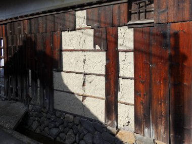 Yıpranmış ahşap duvar binanın dışında doku ve gölgeleri gösteriyor.