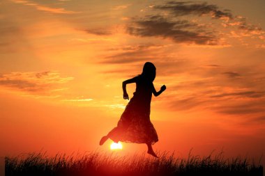 Gün batımında tarlaya atlayan kadın. 