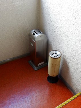 Metalik çöp kutusu ve kül tablası kırmızı zeminde.