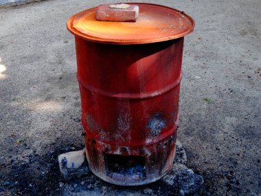 Çakıl taşı yüzeyinde duran paslı metal fıçı.