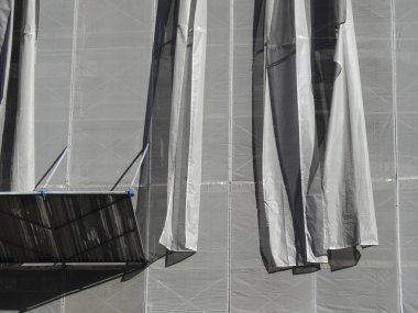 Metal iskelenin yanında asılı gri inşaat brandaları.