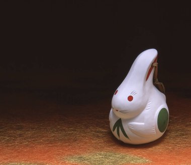 Turuncu bir yüzeyde dekoratif detaylarla seramik tavşan heykelciği