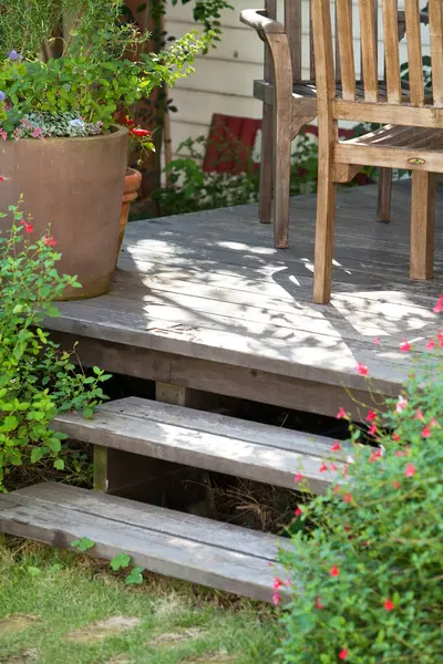 Çiçek açan yeşil bitkilerle çevrili güneşli ahşap merdivenler.