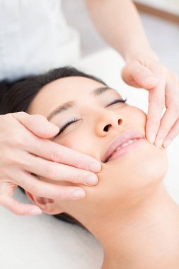 Güzel Asyalı kadın spa salonunda yüz masajı yaptırıyor.