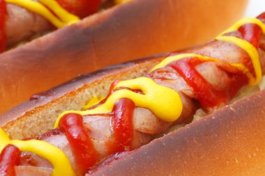 Ketçap ve hardallı lezzetli sosisli sandviçlerin yakın plan görüntüsü.    