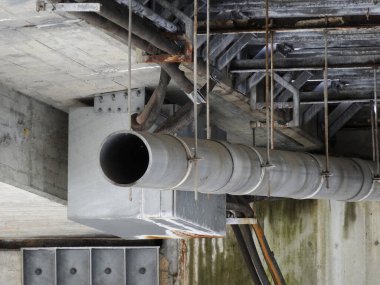 Beton tavan yapısı boyunca uzanan büyük endüstriyel metal boru.
