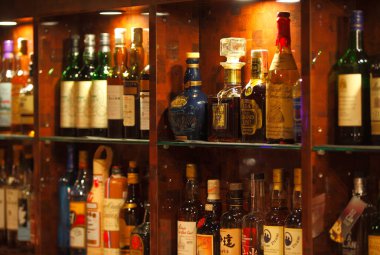 Bar raflarında arka arkaya içki şişeleri.