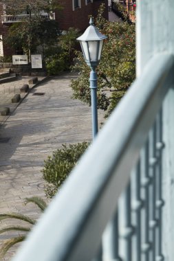 Dışarıdaki dekoratif korkulukların yanında mavi sokak lambası.