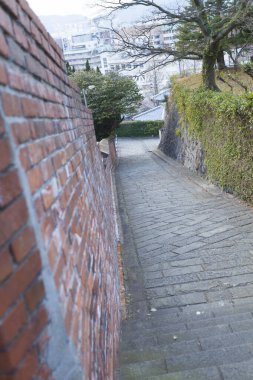 Kırmızı tuğla duvar ve yeşilliğin yanında eğimli taş patika