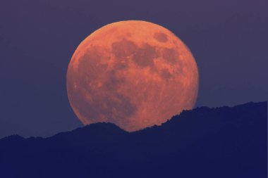 Büyük dolunay dağların üzerinden yükseliyor.